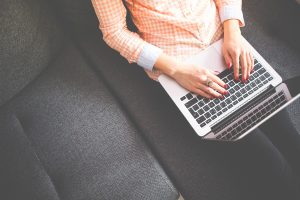 Person leaning back on couch with feet propped and laptop